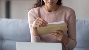 Close-up of a young brunette woman reading mortgage junk mail at home.