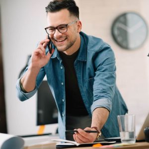 A brunette Missouri Business Owner on the phone at his desk, smiling 